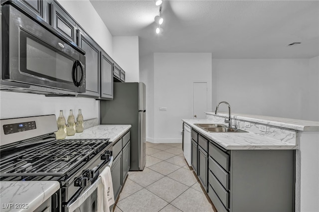 kitchen featuring sink, an island with sink, stainless steel appliances, a textured ceiling, and rail lighting