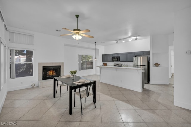 tiled dining room with ceiling fan and a fireplace