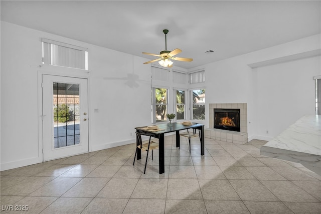 tiled dining area featuring ceiling fan, a fireplace, and plenty of natural light