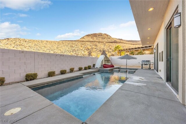 view of pool featuring a grill, a mountain view, and a patio