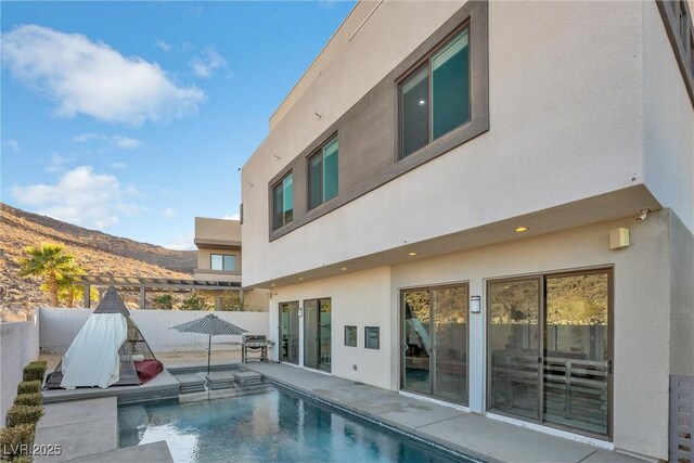 back of house featuring a mountain view, a fenced in pool, and a patio