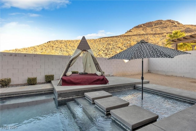 view of swimming pool with pool water feature, a mountain view, and a patio