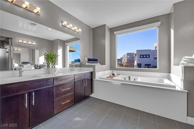 bathroom featuring vanity, tile patterned flooring, and a bath