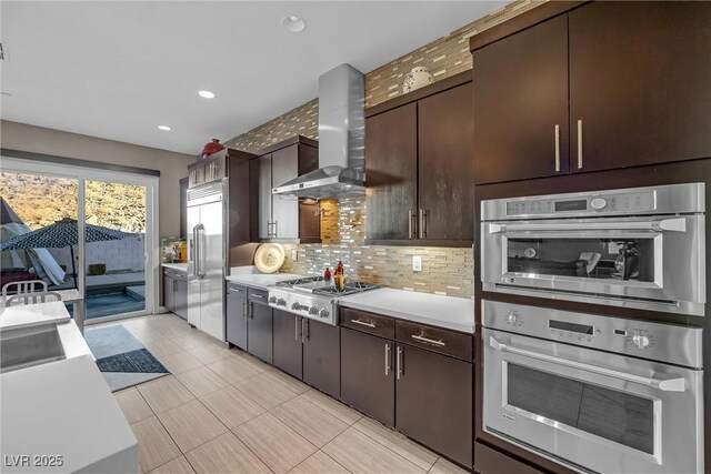 kitchen featuring decorative backsplash, dark brown cabinetry, appliances with stainless steel finishes, and wall chimney exhaust hood