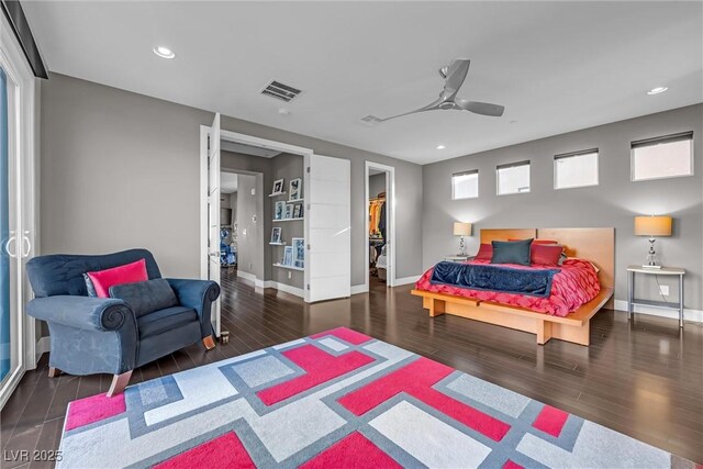 bedroom featuring a spacious closet, dark hardwood / wood-style floors, a closet, and ceiling fan