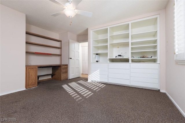 unfurnished living room featuring ceiling fan, built in shelves, and dark colored carpet