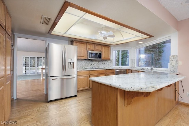 kitchen featuring stainless steel appliances, decorative backsplash, sink, kitchen peninsula, and a tray ceiling