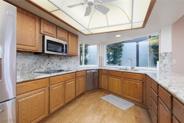 kitchen with tasteful backsplash, ceiling fan, light hardwood / wood-style floors, sink, and appliances with stainless steel finishes