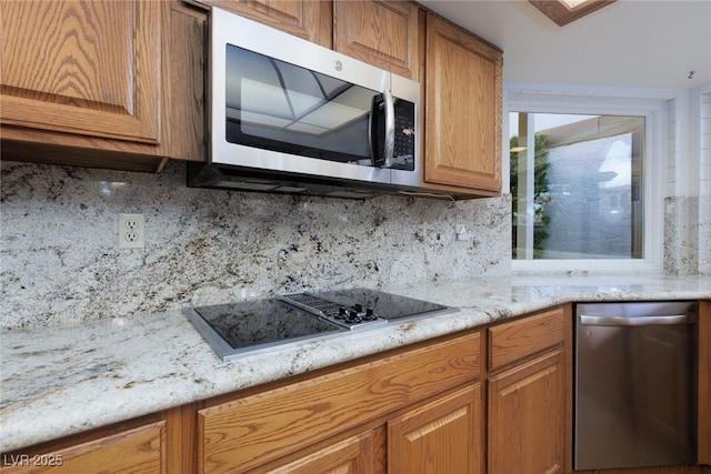 kitchen featuring decorative backsplash, appliances with stainless steel finishes, and light stone counters