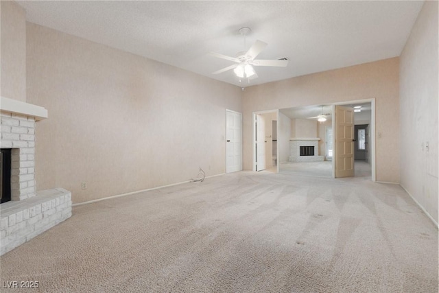 unfurnished living room with a brick fireplace, light colored carpet, and ceiling fan