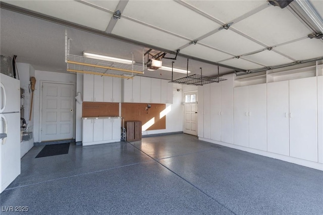 garage featuring white refrigerator and a garage door opener