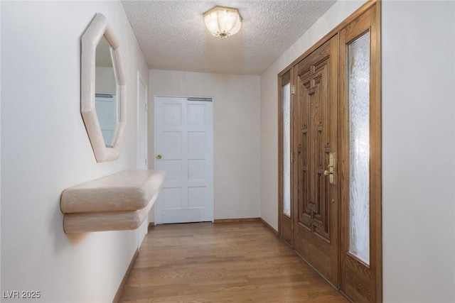 hallway with a textured ceiling and light hardwood / wood-style floors