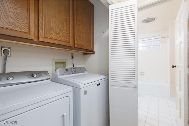 laundry room with washer and dryer, cabinets, and light tile patterned floors