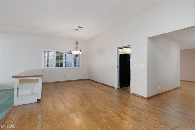 empty room featuring a textured ceiling and light hardwood / wood-style flooring