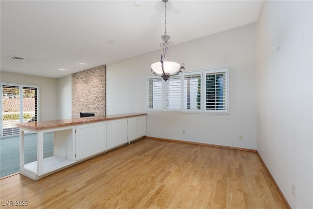 spare room featuring light wood-type flooring and a stone fireplace