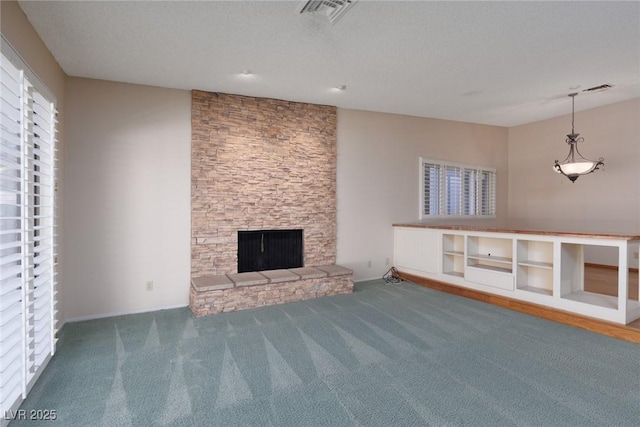 unfurnished living room featuring carpet floors, a stone fireplace, and a textured ceiling