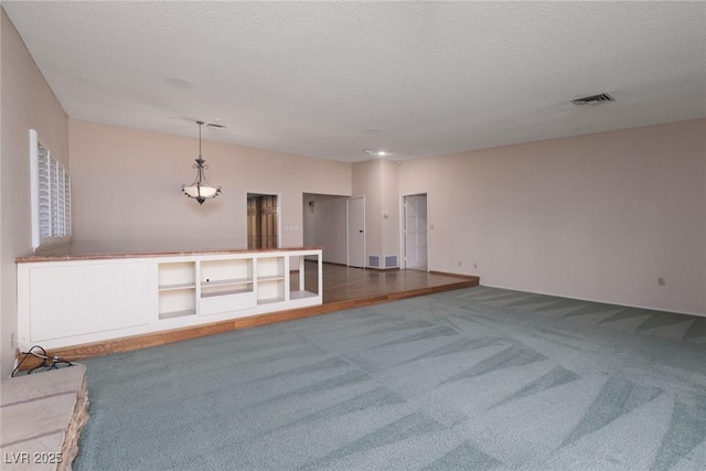 unfurnished living room featuring a textured ceiling and dark colored carpet