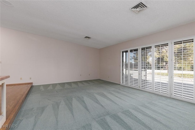 carpeted empty room with a textured ceiling