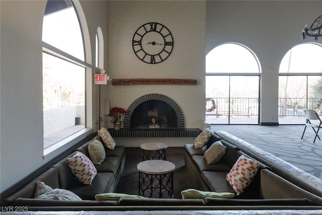 living room featuring a brick fireplace and a high ceiling