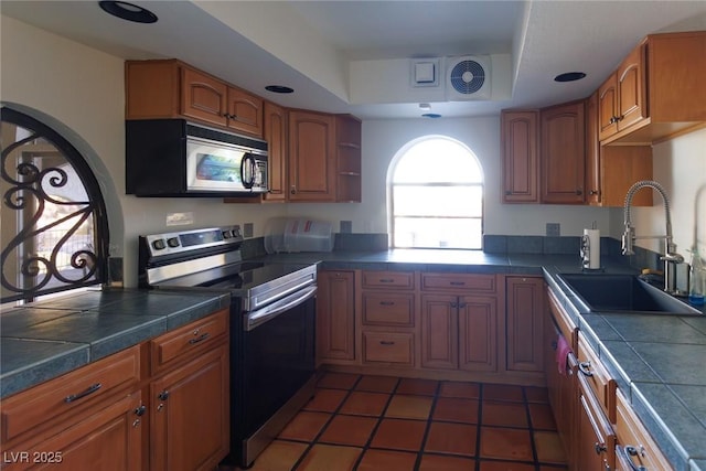 kitchen with dark tile patterned flooring, sink, a tray ceiling, and stainless steel range with electric stovetop