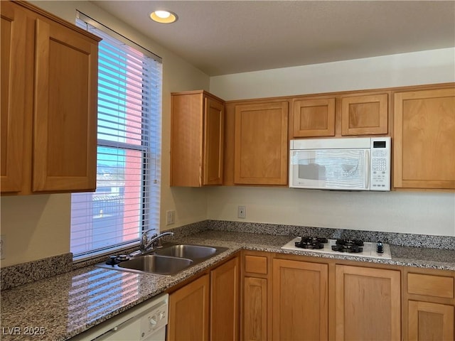 kitchen featuring stone countertops, sink, and white appliances