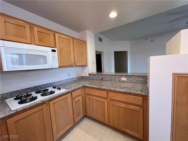 kitchen featuring light stone countertops and white appliances