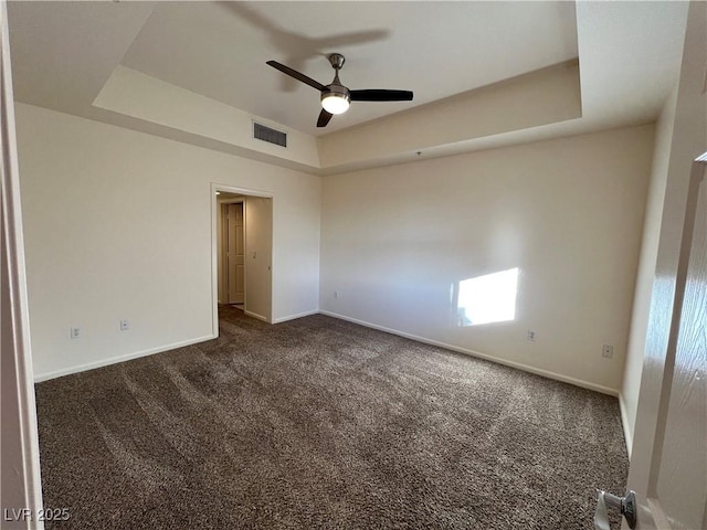 carpeted empty room featuring a raised ceiling and ceiling fan