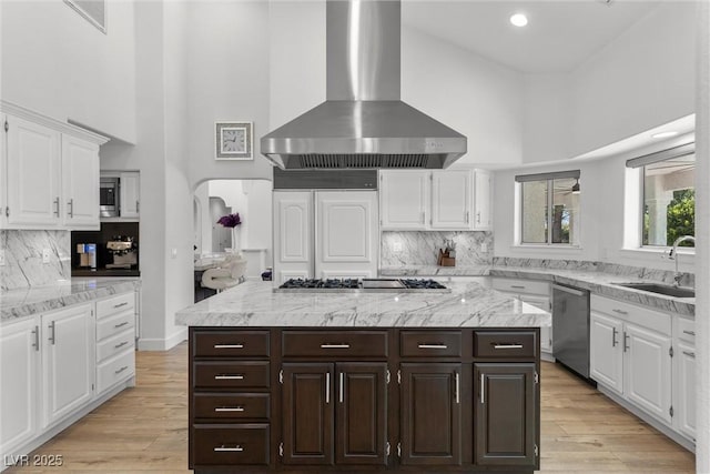 kitchen with extractor fan, a kitchen island, white cabinetry, stainless steel appliances, and sink