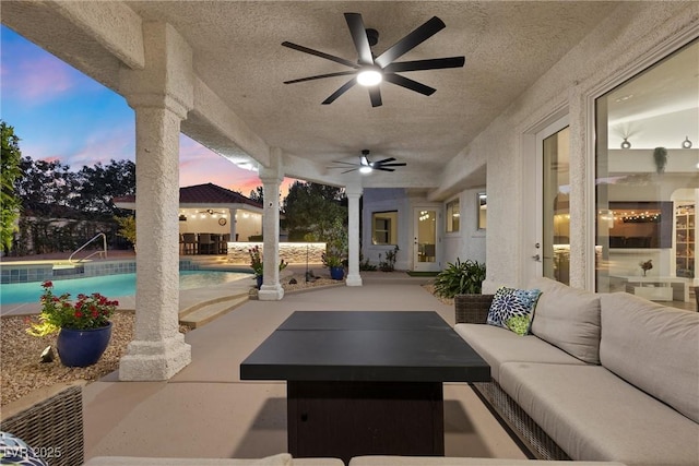 patio terrace at dusk featuring ceiling fan and an outdoor hangout area