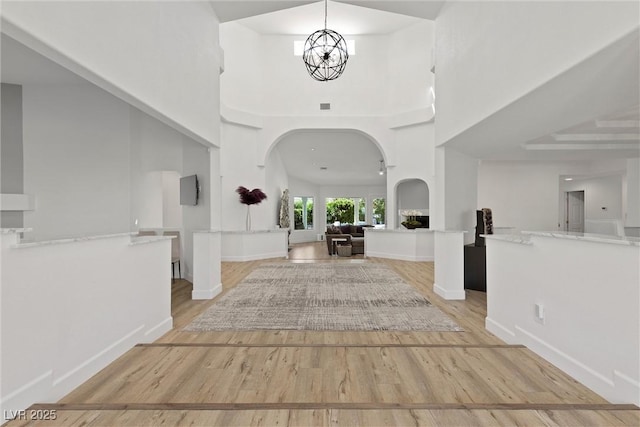 foyer entrance featuring an inviting chandelier, light hardwood / wood-style flooring, and a high ceiling