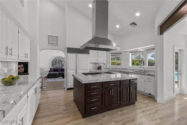 kitchen featuring backsplash, sink, white cabinetry, dark brown cabinets, and island range hood