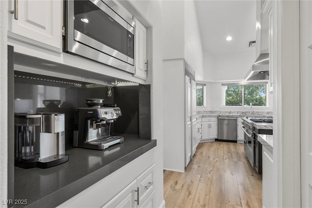 kitchen with light wood-type flooring, appliances with stainless steel finishes, sink, and white cabinetry