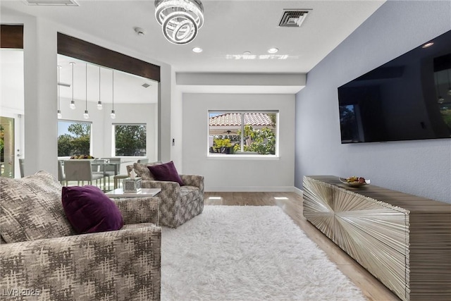 living room featuring an inviting chandelier, a healthy amount of sunlight, and light hardwood / wood-style floors