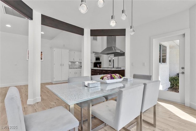 dining room with light hardwood / wood-style flooring and beamed ceiling