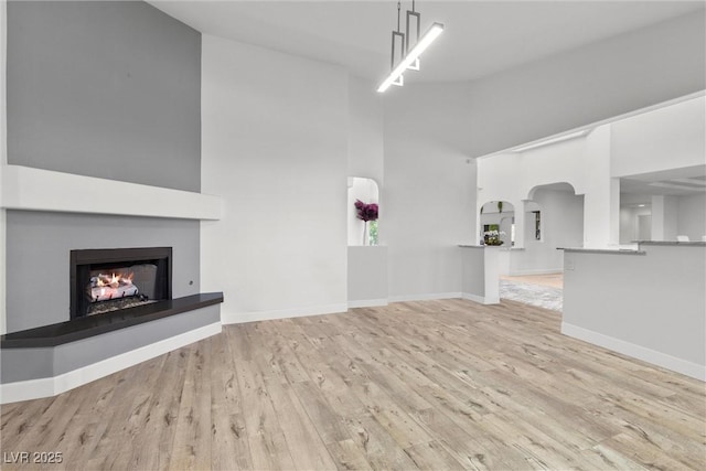 unfurnished living room featuring a towering ceiling and light hardwood / wood-style flooring