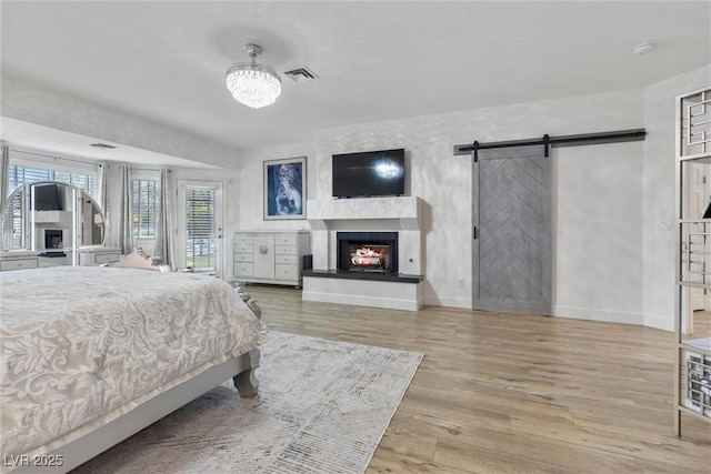 bedroom with a chandelier, a barn door, and light wood-type flooring