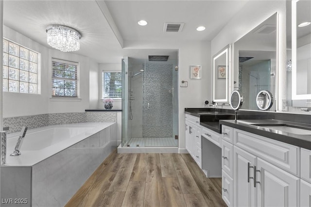 bathroom with wood-type flooring, independent shower and bath, vanity, and a notable chandelier