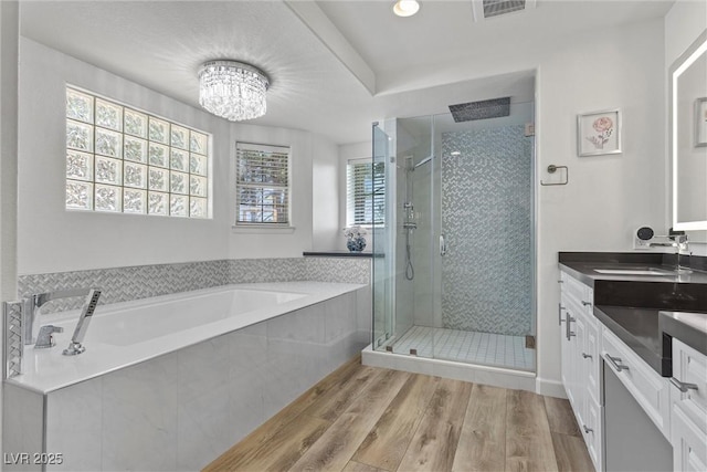 bathroom featuring vanity, an inviting chandelier, plus walk in shower, and hardwood / wood-style flooring