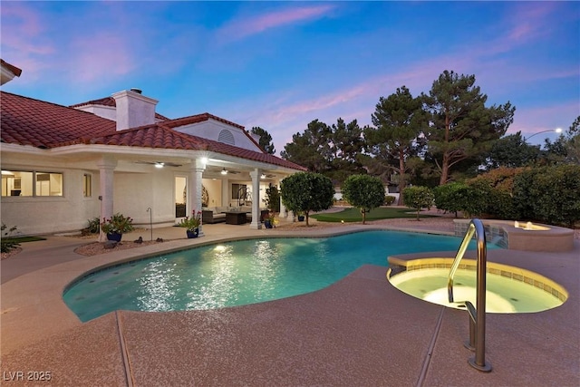 pool at dusk with an in ground hot tub, a patio area, outdoor lounge area, and ceiling fan