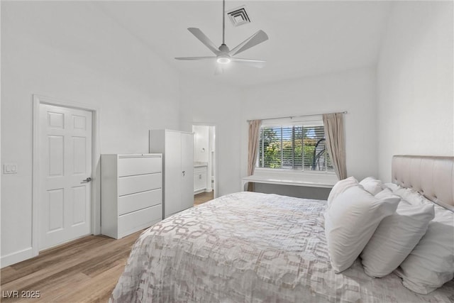 bedroom with ceiling fan, wood-type flooring, connected bathroom, and high vaulted ceiling