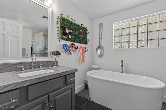 bathroom with a tub to relax in, vanity, and tile patterned flooring