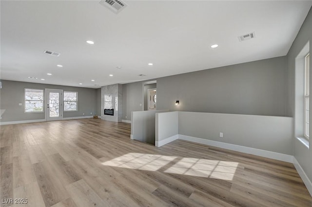 unfurnished room featuring a fireplace and light hardwood / wood-style flooring