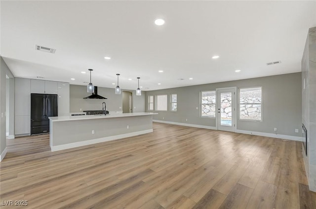 unfurnished living room featuring ceiling fan, light hardwood / wood-style floors, and sink