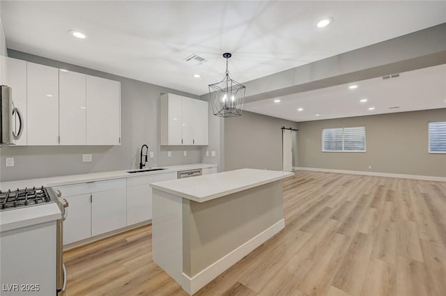 kitchen with a kitchen island, white cabinetry, sink, hanging light fixtures, and a barn door