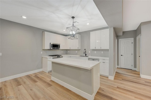 kitchen featuring hanging light fixtures, sink, white cabinetry, and a center island