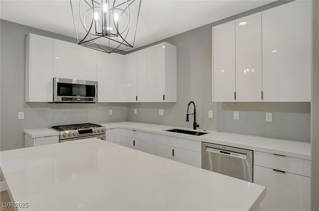 kitchen featuring appliances with stainless steel finishes, pendant lighting, white cabinets, and sink