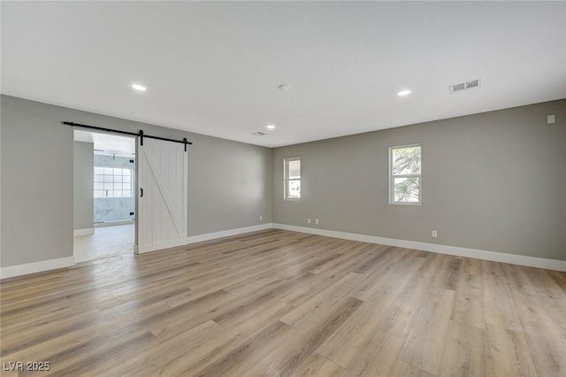 unfurnished room featuring light wood-type flooring and a barn door