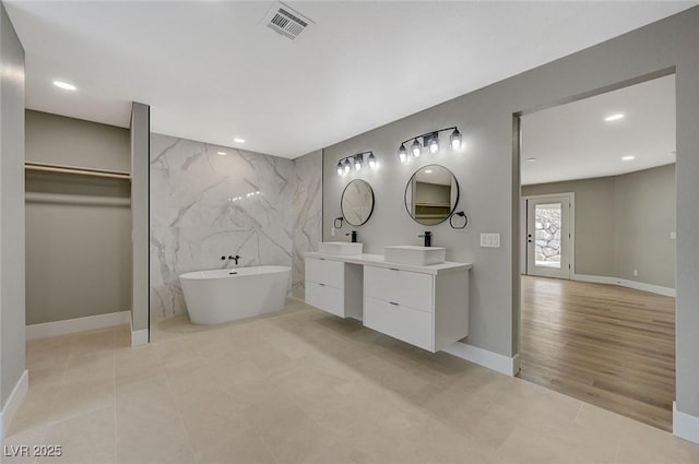 bathroom featuring a bathing tub, tile walls, and vanity