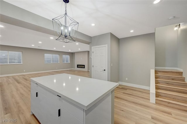 kitchen featuring a center island, an inviting chandelier, light hardwood / wood-style flooring, hanging light fixtures, and white cabinets