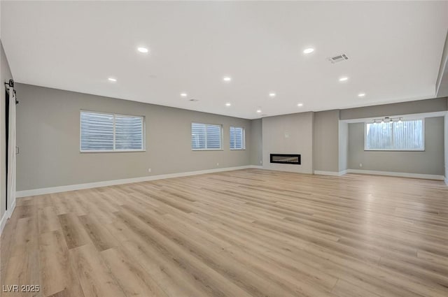 unfurnished living room featuring light hardwood / wood-style floors and a barn door